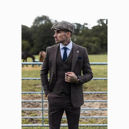Man wearing a dark brown tailored suit with a matching waistcoat, white shirt, and checkered cap, suitable for formal or outdoor events