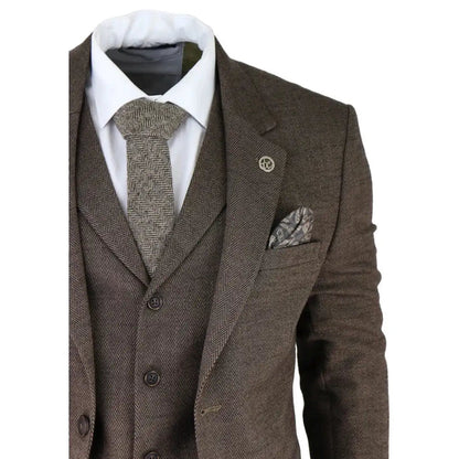 Men's brown herringbone tweed suit with blazer, waistcoat, and matching trousers, paired with a white shirt and patterned tie, tailored fit