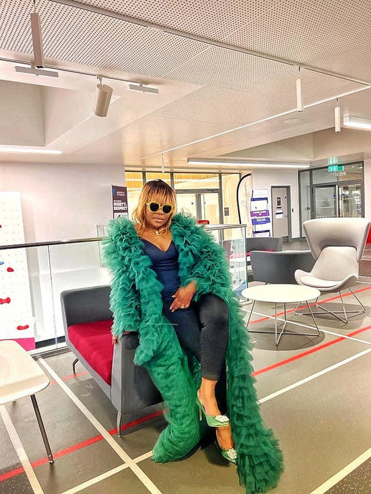 Emerald tiered tulle statement coat styled over black outfit with layered volume