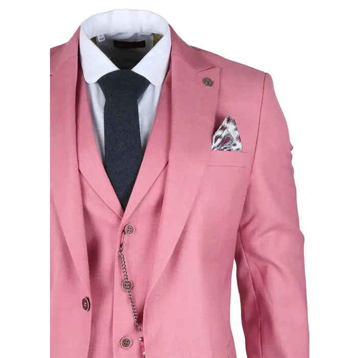 Close-up of a men's pink tailored fit 3-piece suit with a white dress shirt, dark gray tie, and a patterned pocket square, featuring lapel pin and chain detail