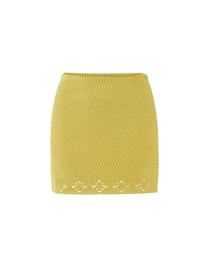 The JANAI SKIRT - YELLOW : LEMON from TIGERMIST is a bright yellow, knee-length skirt featuring a textured fabric pattern. The hemline includes a decorative diamond and floral cut-out design for added detail, and the skirt has a form-fitting silhouette.