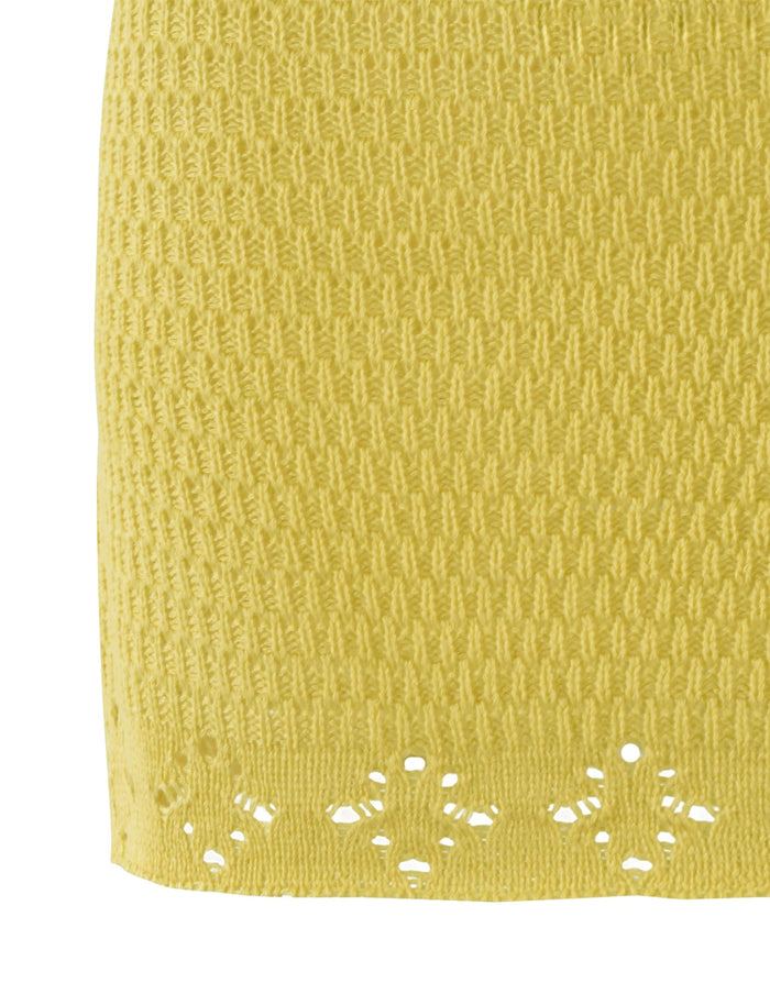 Close-up of a yellow knitted fabric with a textured pattern. The bottom edge features a decorative, open-knit floral design, reminiscent of TIGERMIST's intricate detailing found on the JANAI SKIRT - YELLOW : LEMON.