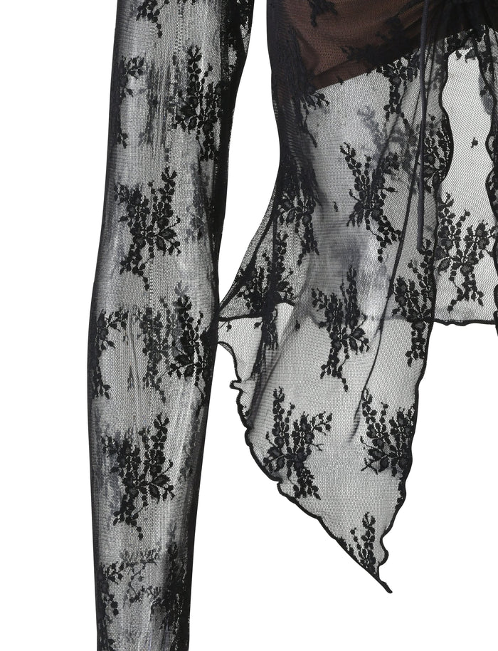 Close-up of a black Tiger Mist Karolina Long Sleeve Top, featuring an exquisite floral lace pattern. The sheer lace material showcases edges with an uneven, scalloped finish. The white background accentuates the intricate details of the fabric.