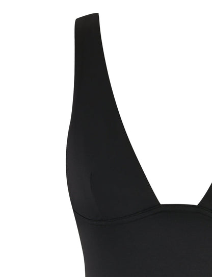 The image showcases a close-up of the LUNARIA MINI DRESS - BLACK from TIGERMIST. The focus is on the upper portion, highlighting the seam and smooth fabric. The dress features a deep V neckline and is designed with a fitted style.