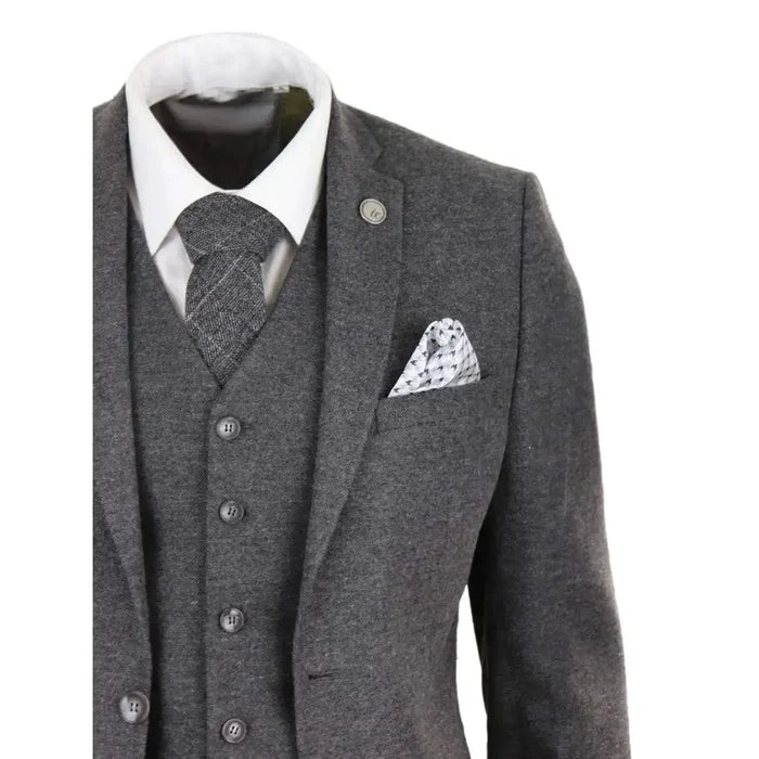 Close-up of men's grey wool tweed waistcoat with black trim, paired with a white shirt and patterned tie, showcasing classic vintage style