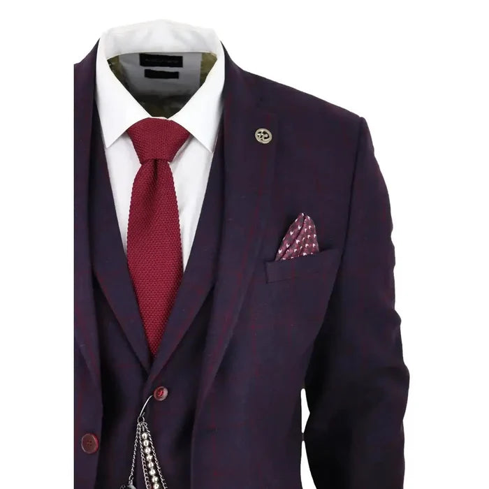 Men's tailored suit jacket in dark plum wine tweed with subtle check pattern, featuring a lapel pin, pocket square, and a red textured tie