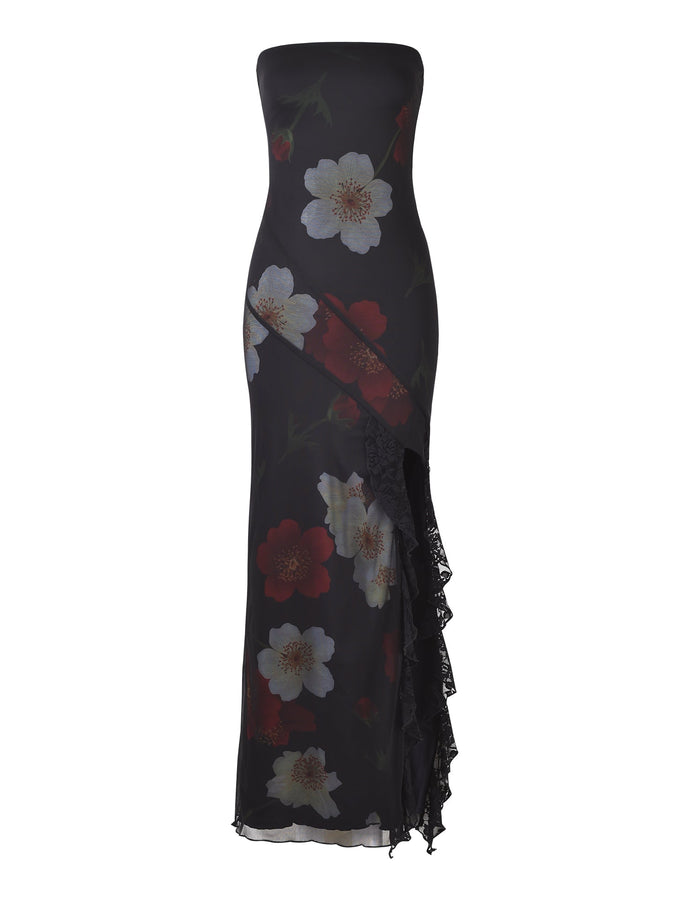 Introducing the THEO MAXI DRESS - RED: MACRO FLORAL by TIGERMIST, a strapless, floor-length black dress intricately adorned with a bold white and red floral pattern. This sophisticated creation features an asymmetrical design complemented by a lace-trimmed slit on the left side, adding an elegant touch to your ensemble.