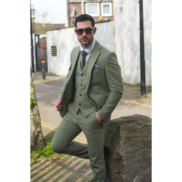 Male model wearing a sage green 3-piece linen suit with matching blazer, vest, and pants, styled for a formal outdoor event