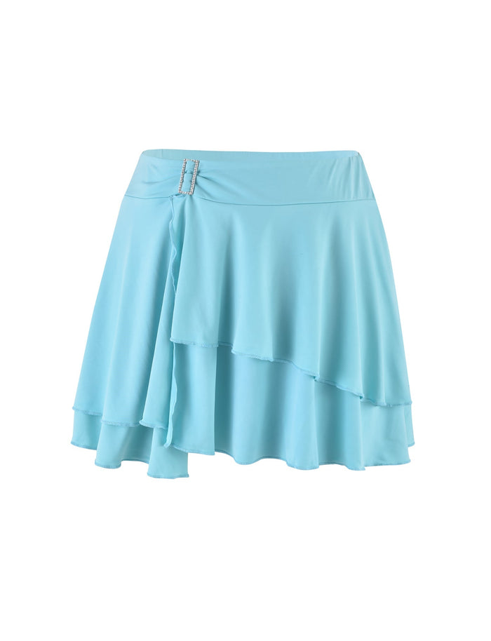 The VERANIQUE SKIRT - BLUE from TIGERMIST is a light blue, layered mini skirt featuring two silver buckles on one side. The skirt boasts an overlapping design with soft, flowing fabric that drapes asymmetrically at the front, delivering a stylish and playful look.
